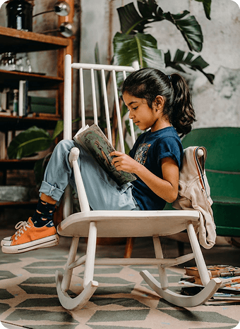 A child reading a book in a rocking chair
