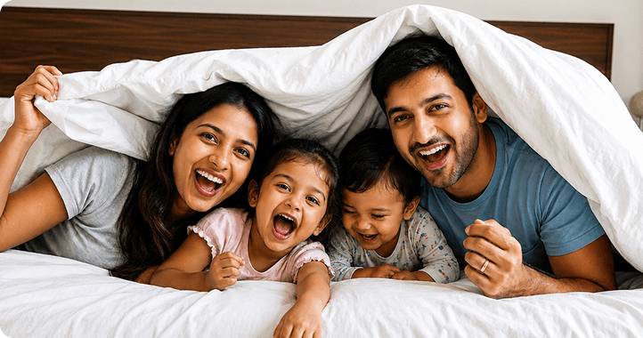 A family laughing together under a duvet