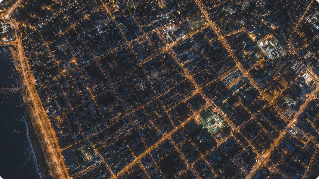 An aerial view of a city at night, its street grid picked out in orange light